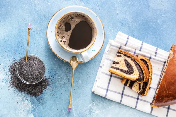 Kopje koffie en smakelijk broodje met poppy zaden op tafel — Stockfoto