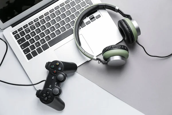 Laptop, Gamepad und Kopfhörer auf grauem Hintergrund — Stockfoto