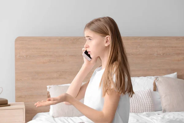 Roztomilá mladá dívka, která mluví mobilním telefonem v ložnici doma — Stock fotografie