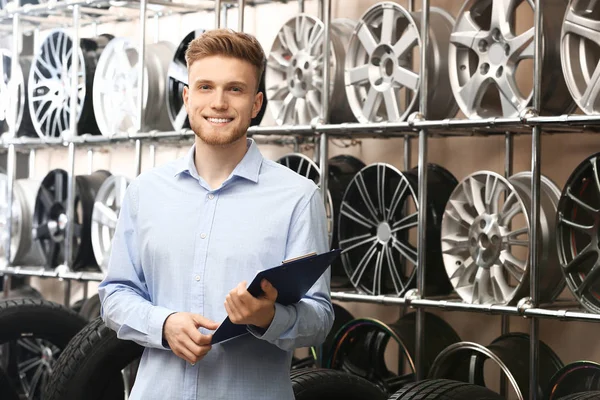 Hombre vendedor en tienda de neumáticos de coche — Foto de Stock