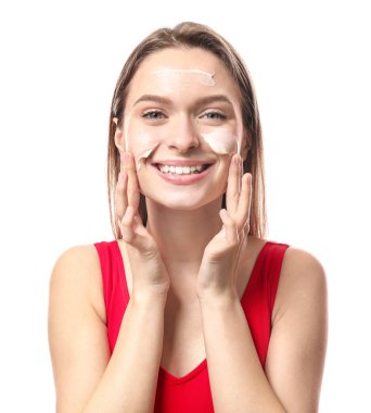 Beyaz arka plana karşı güneş koruma kremi uygulayarak güzel genç kadın