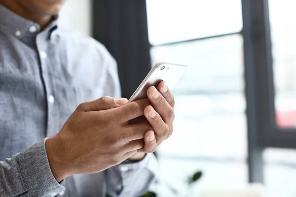 Afro-Amerikaanse man met mobiele telefoon in kantoor, close-up — Stockfoto