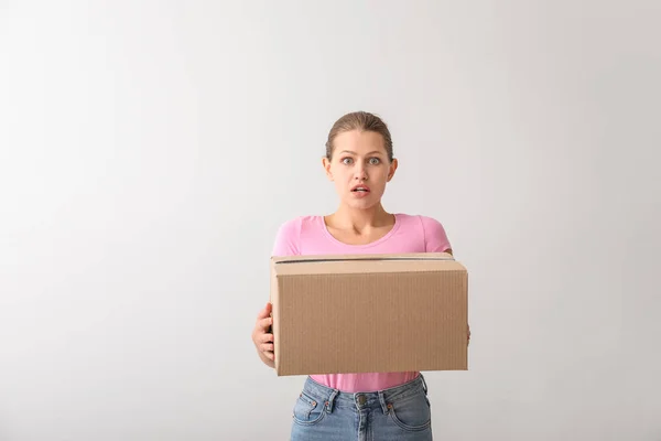 Mujer conmocionada con caja de cartón sobre fondo claro —  Fotos de Stock