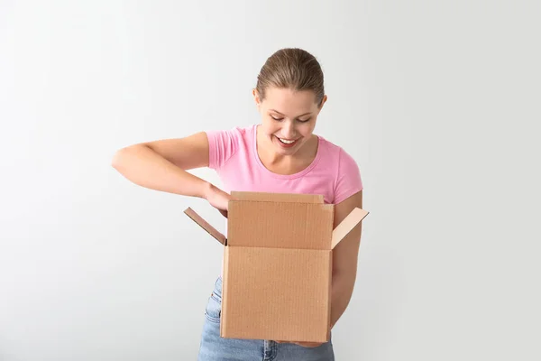 Young woman with cardboard box on light background — Stock Photo, Image