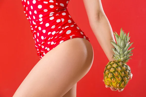 Beautiful young woman in swimming suit and with pineapple on color background — Stock Photo, Image