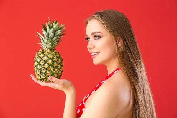 Beautiful young woman in swimming suit and with pineapple on color background — Stock Photo, Image