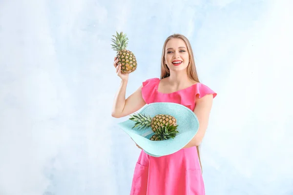 Mooie jonge vrouw met ananassen op kleur achtergrond — Stockfoto