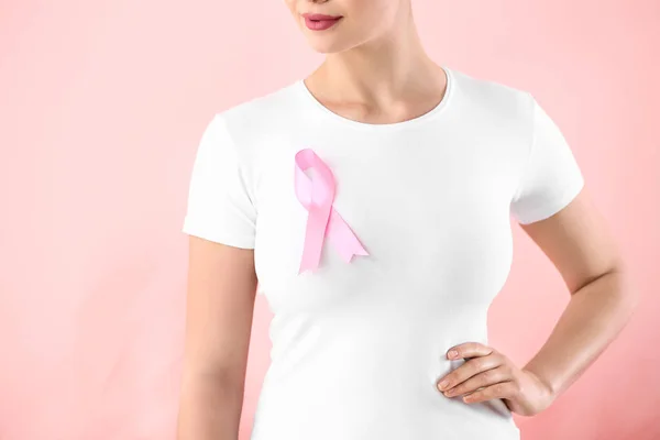 Giovane donna con nastro rosa su sfondo colore. Concetto di sensibilizzazione sul cancro al seno — Foto Stock