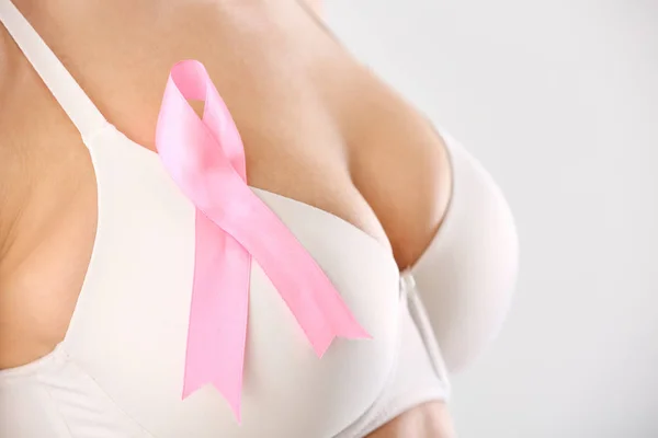Jovem com fita rosa sobre fundo branco, close-up. Conceito de consciência do câncer de mama — Fotografia de Stock