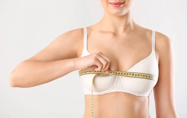 Jonge vrouw meten van haar borst op witte achtergrond — Stockfoto