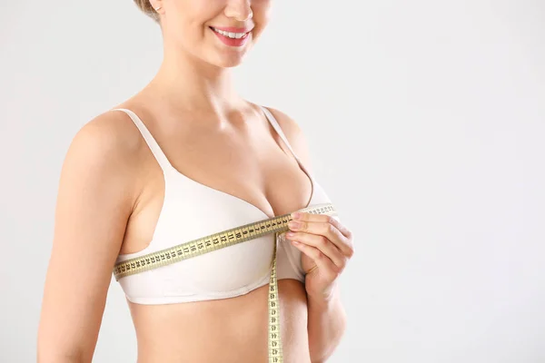 Young woman measuring her breast on white background — Stock Photo, Image