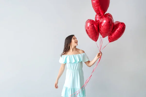 Mujer joven feliz con globos de aire sobre fondo claro — Foto de Stock