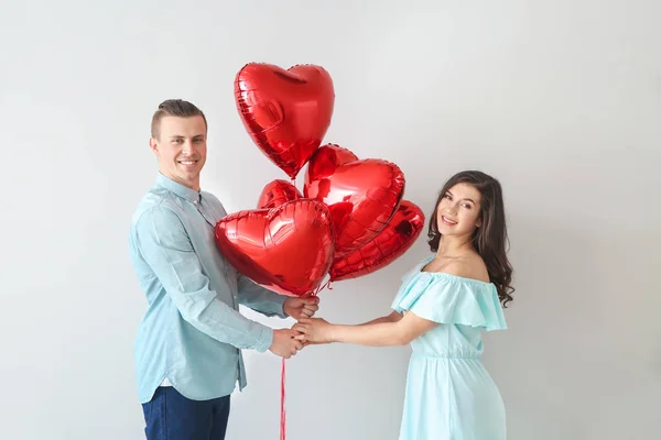 Счастливая молодая пара с воздушными шарами на светлом фоне — стоковое фото