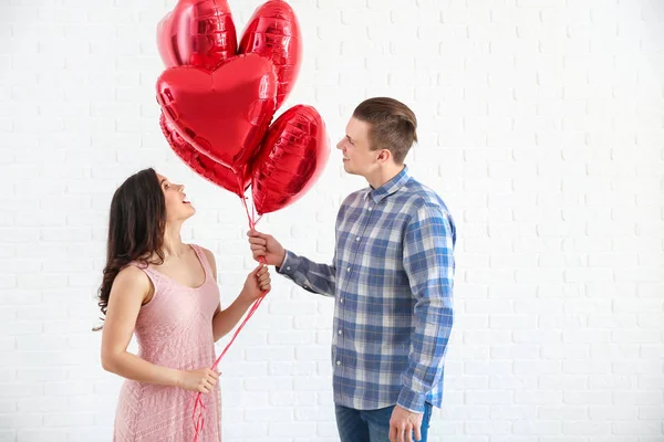 Jovem casal feliz com balões de ar no fundo branco — Fotografia de Stock