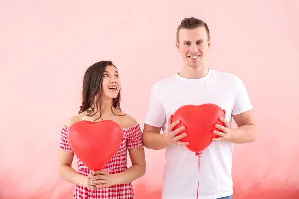 Feliz pareja joven con globos de aire sobre fondo de color —  Fotos de Stock