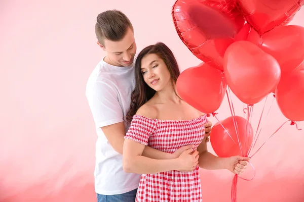 Feliz pareja joven con globos de aire sobre fondo de color —  Fotos de Stock