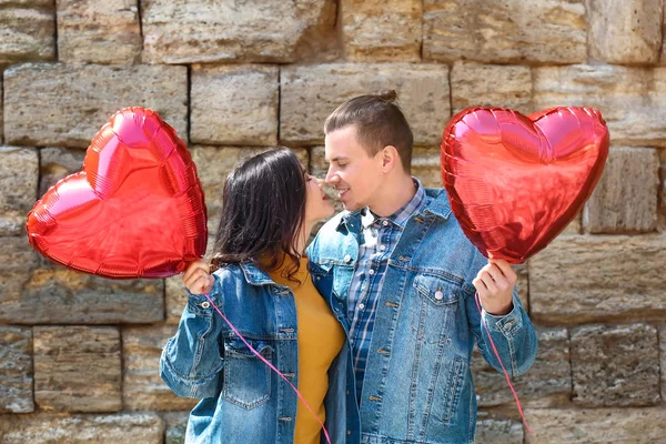 Feliz pareja joven con globos de aire en forma de corazón al aire libre — Foto de Stock