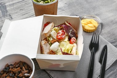 Gri arka planda lezzetli yiyecekler içeren konteyner