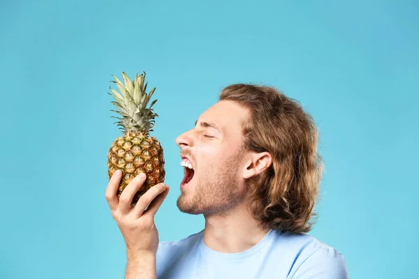 Handsome man with pineapple on color background — Stock Photo, Image