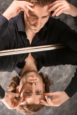 Şık genç adam cam yüzeyli masada oturan şık giysiler