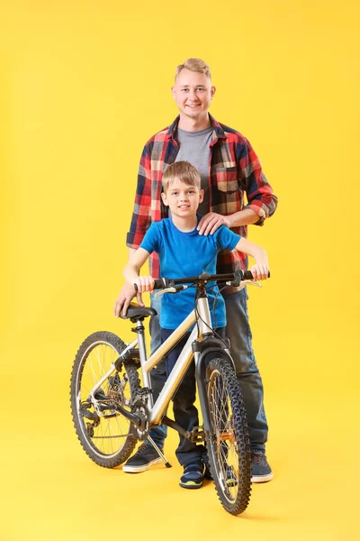 色の背景に自転車を持つ父と彼の息子 — ストック写真
