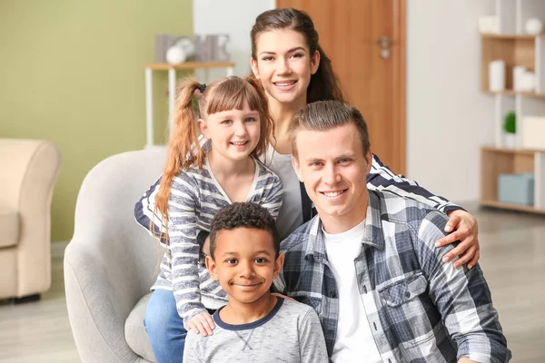 Glückliches Paar mit kleinen Adoptivkindern zu Hause — Stockfoto