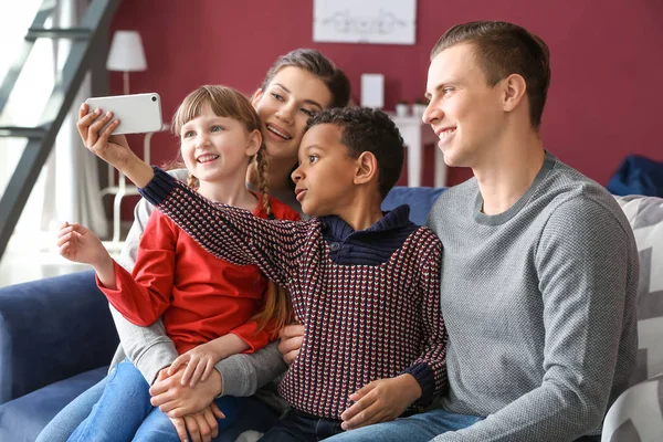 Ευτυχισμένο ζευγάρι με υιοθετά παιδιά παίρνοντας selfie στο σπίτι — Φωτογραφία Αρχείου