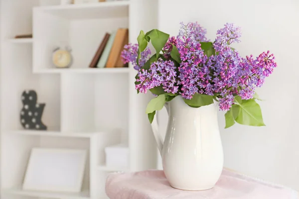 Jug with beautiful lilac flowers indoors — Stock Photo, Image