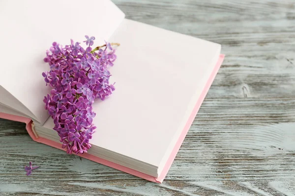 Book with beautiful lilac flowers on wooden table