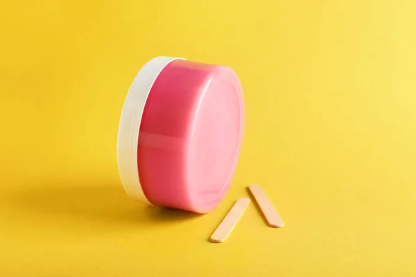 Container with sugaring paste for epilation on color background