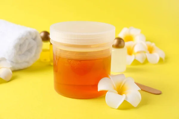 Container with sugaring paste for hair removal on color background