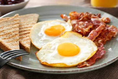 Tabak lezzetli kızarmış yumurta, pastırma ve masada tost, closeup ile