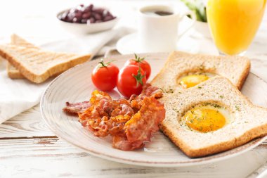 Ahşap arka plan üzerinde lezzetli kızarmış yumurta, pastırma, tost ve domates ile Tabak