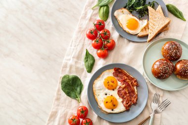 Tabloda lezzetli kızarmış yumurta, pastırma ve çörekler ile Kompozisyon