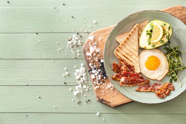 Tabak lezzetli kızarmış yumurta, pastırma, avokado ve masada tost ile
