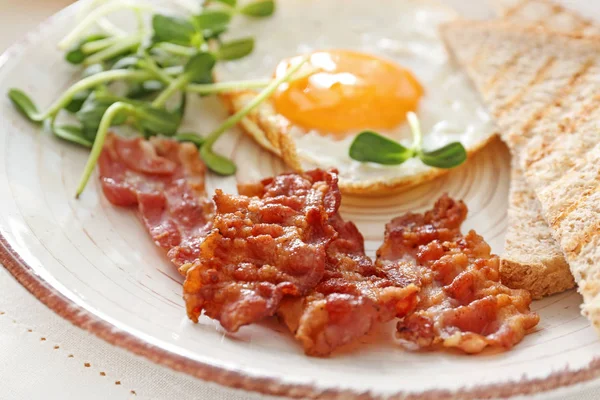 Prato com ovo frito saboroso, bacon e torradas na mesa, close-up — Fotografia de Stock