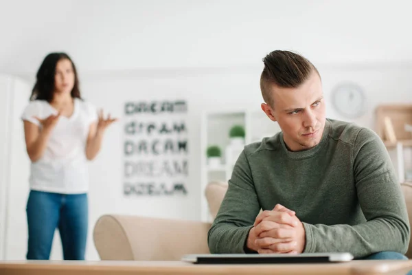 Junge Frau beschimpft ihren traurigen Mann zu Hause — Stockfoto