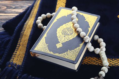 Ahşap arka planda Müslüman dua paspas, boncuk ve Kur'an