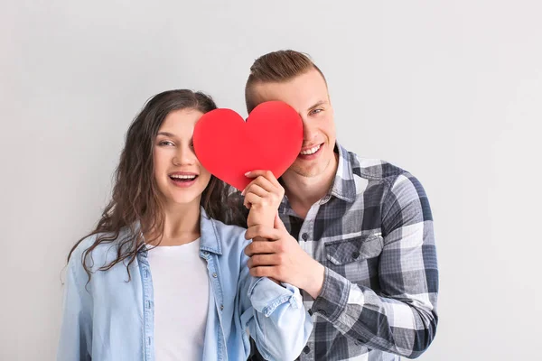 Adorable pareja amorosa con corazón de papel sobre fondo gris —  Fotos de Stock
