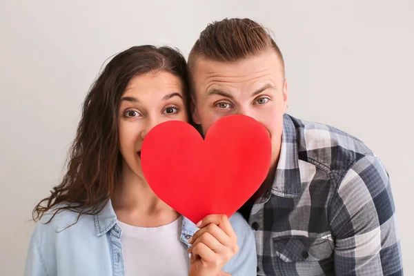 Adorável casal amoroso com coração de papel no fundo cinza — Fotografia de Stock