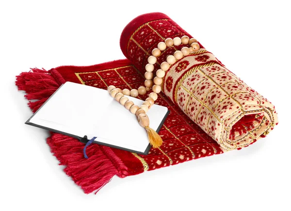 Muslim prayer mat, beads and Koran on white background