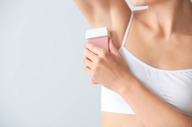 Güzel genç kadın hafif arka plan üzerinde koltuk altı epilasyon, closeup