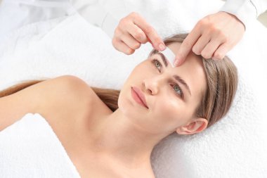 Güzellik salonunda kaş epilasyonu olan genç bir kadın.