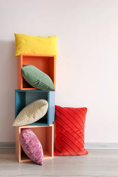 Shelf unit with soft pillows near light wall — Stock Photo, Image