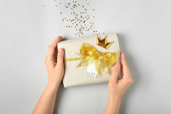 Weibliche Hände mit schönem Geschenkkarton auf hellem Hintergrund — Stockfoto