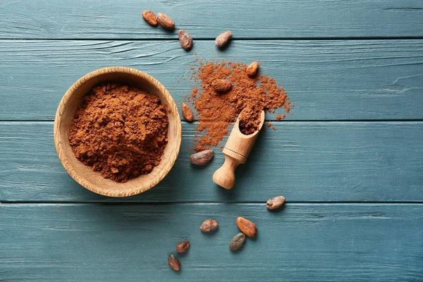 Miska s kakaovým práškem a naběračkou na dřevěné pozadí — Stock fotografie