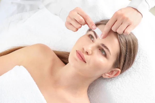 Young woman undergoing eyebrows epilation in beauty salon — Stock Photo, Image