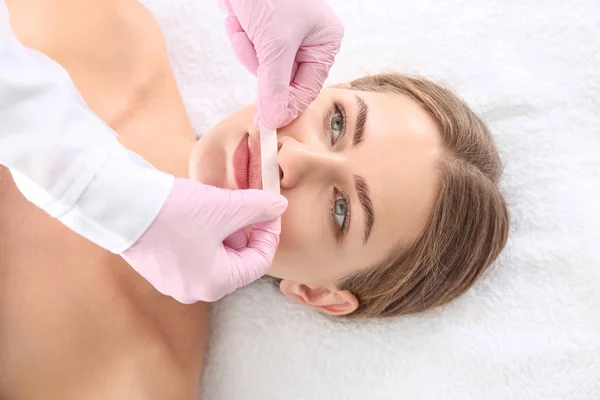 Косметолог видаляє волосся над верхньою губою молодої жінки в салоні — стокове фото