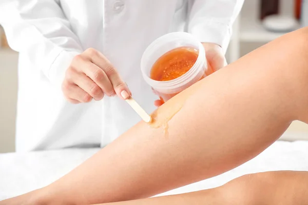 Beautician epilating legs of young woman in salon — Stock Photo, Image