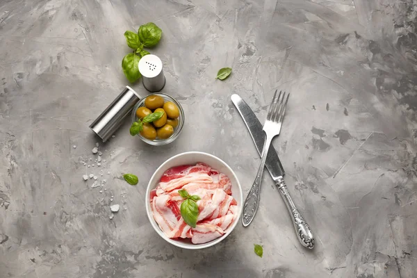 Composition with fresh raw bacon and olives on grey background — Stock Photo, Image
